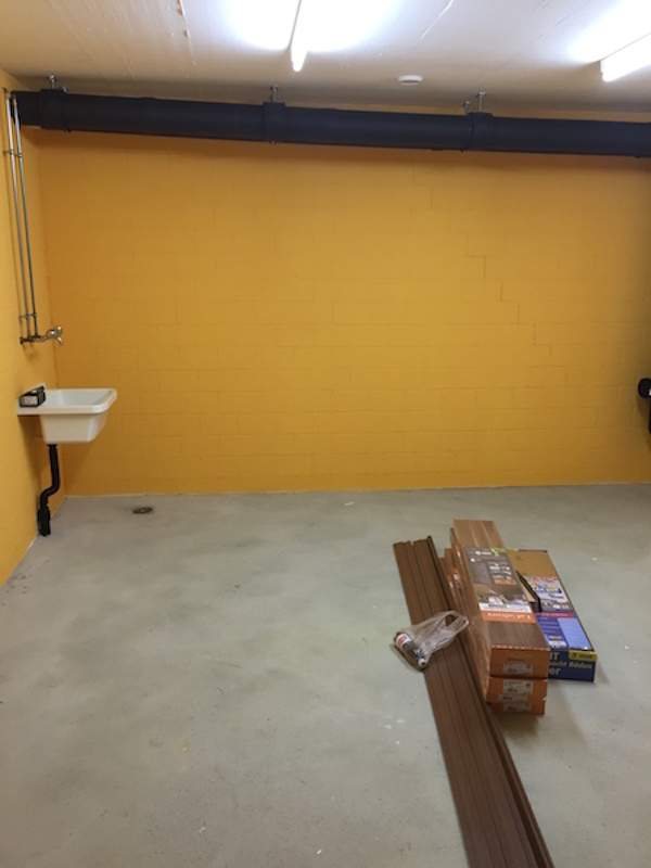 Zimmer mit orangen Wänden und kahlem Boden, Kartons am Rand