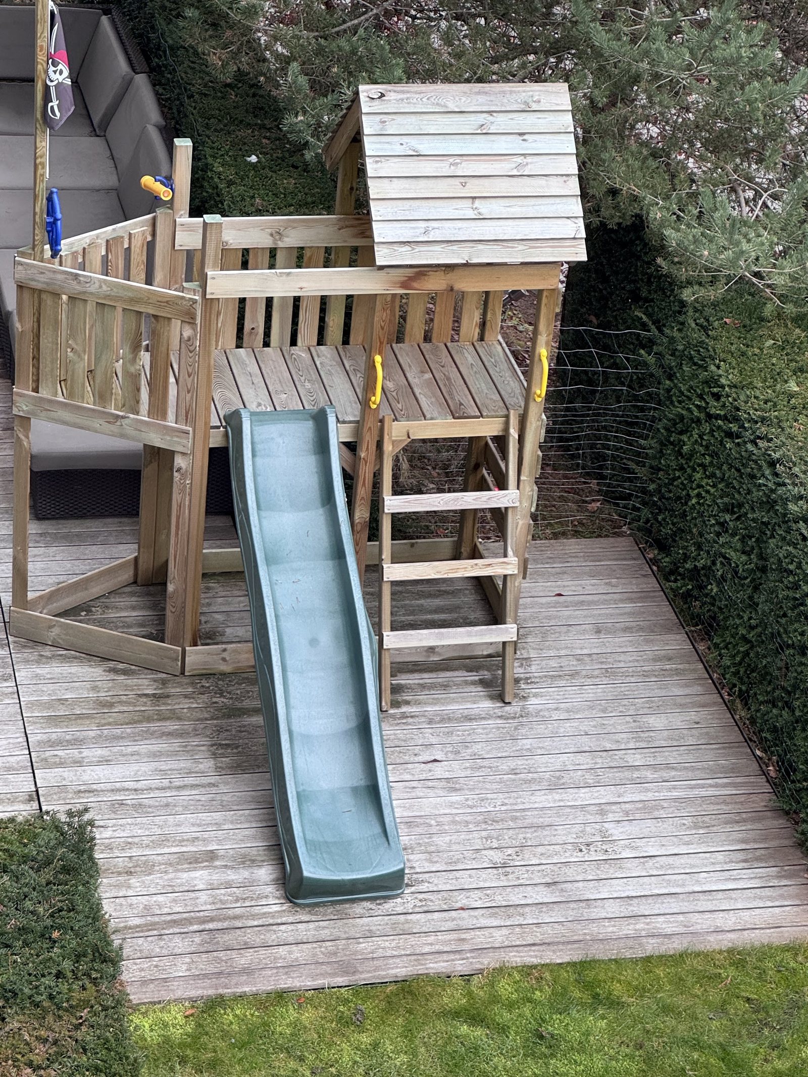 Spielhaus mit Rutsche auf einem Holzdeck im Garten